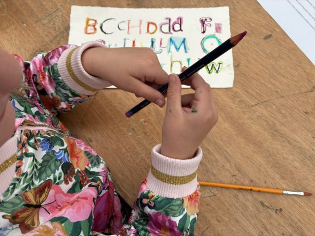 Using watercolour pencils to colour the lettering. Marian Haf print workshop for children at 2026 Eisteddfod
